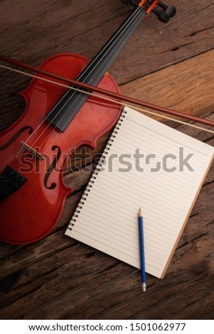 Close-up shot violin orchestra instrumental and notebook over wooden background select focus shallow depth of field