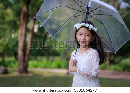 Little Asian girl holding clear umbrella and smiling with happiness select focus shallow depth of field