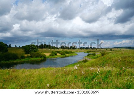 Beautiful landscape with river and dark stormy clouds over the land