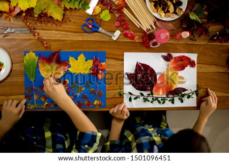 Children, applying leaves using glue, scissors, and paint, while doing arts and crafts in school, autumntime