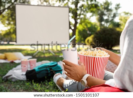 Woman with popcorn watching movie in open air cinema, closeup. Space for text