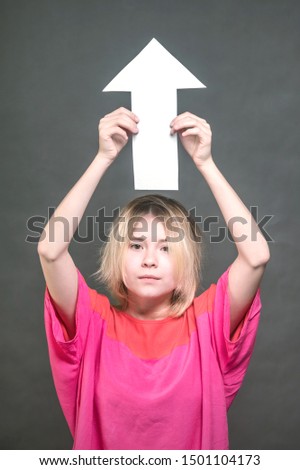 Blonde teenager holds a white arrow up above her head. Toned