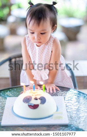 Little baby girl kid and panda cake with colorful fire candles on top. birthdays concept.