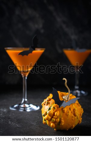 Funny Pumpkin with black bats and orange cocktail in a glass on Halloween