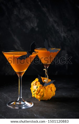 Funny Pumpkin with black bats and orange cocktail in a glass on Halloween