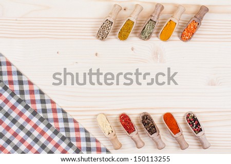 Spices in scoops, tablecloth on wooden background
