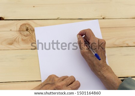 Hands of an elderly man are holding blank paper and a pen. Concept of testament, signing of an agreement, writing in old age. Image. Royalty-Free Stock Photo #1501164860
