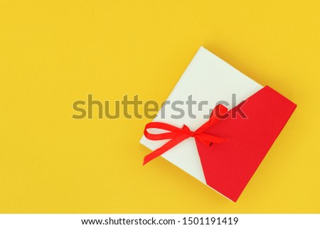 Red with beige gift box on a bright yellow background. Flat lay top view copy space