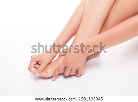Woman massages a sore foot on white background in studio.