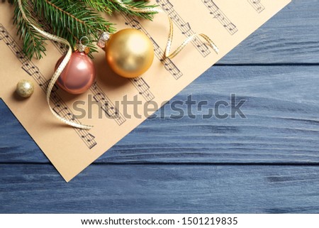 Flat lay composition with Christmas decorations and music sheets on blue wooden table. Space for text