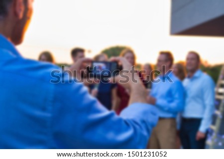Rear view of man taking pictures of colleagues celebrating sucess at rooftop