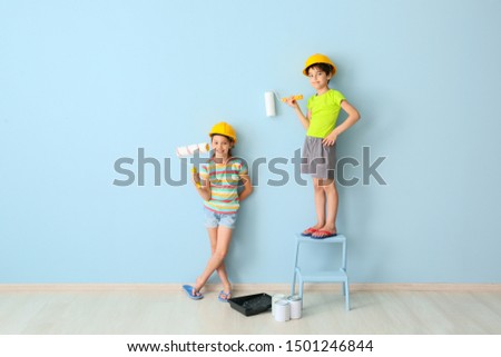 Cute little children painting wall in room