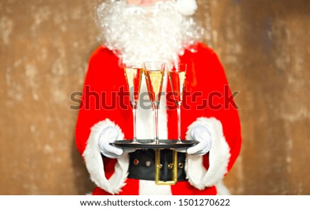 Santa Claus holding champagne glasses on the tray. Closeup 