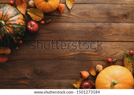 Autumn composition. Pumpkins, dried fall leaves, apples, red berries, walnuts, on wooden table. Happy Thanksgiving concept. Flat lay, top view, copy space