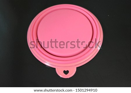 Pink folding and multifunctional rubber plate, a bowl with a plastic edging on a black glossy surface.