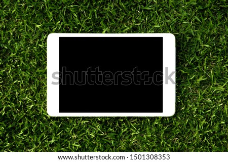 blank screen tablet on green grass background