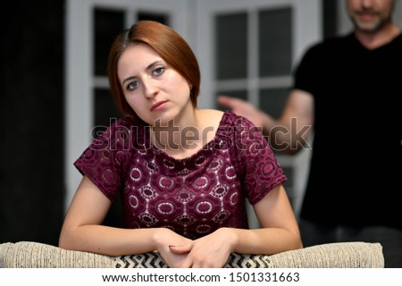 Photo of conflict, family relationships of teenage girl and father in the room. The daughter sits on the sofa at home in various poses and shows discontent.
