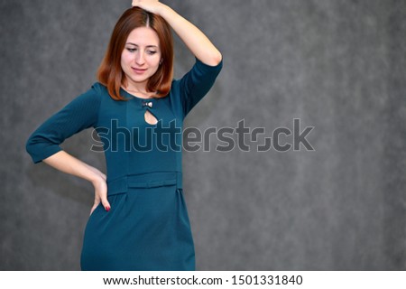 Portrait of a brunette girl with beautiful brown hair in a dark green dress on a white background. Standing in different poses, showing emotions.