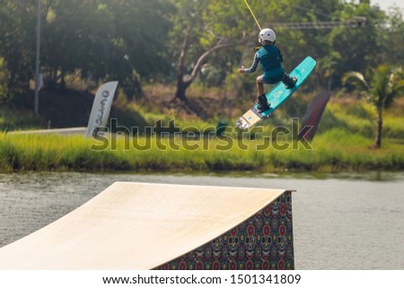 A young girl athlete wakeboarder overcomes an obstacle in the water.