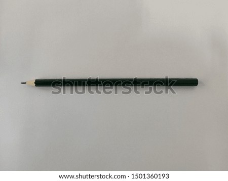 The green pencil is on the white paper.