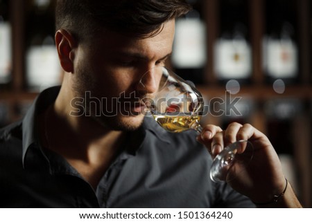 Bokal of white wine on background, male sommelier appreciating drink