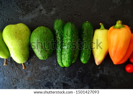 Composition with assorted fresh organic vegetables.
Assorted fresh vegetables and fruits. Place for text. Cucumbers, tomatoes, pears, avocados, carrots, sweet peppers. Food on a dark table background.