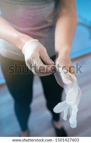 Photo detail of a woman physiotherapist putting two plastic gloves. Concept of muscle health and relaxation. Vertical image