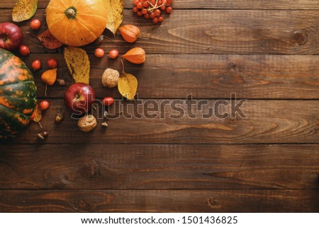 Autumn composition. Pumpkins, fallen leaves, apples, red berries, walnuts on wooden table. Happy Thanksgiving concept. Flat lay, top view, copy space