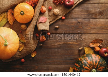 Autumn composition. Pumpkins, sackcloth, fallen leaves, apples, red berries, walnuts on wooden table. Happy Thanksgiving concept. Flat lay, top view, copy space