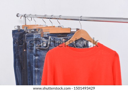 Red sweater with five blue jeans on hanger