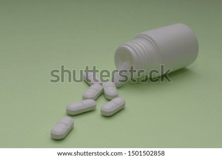 white pills from a container on a colored background