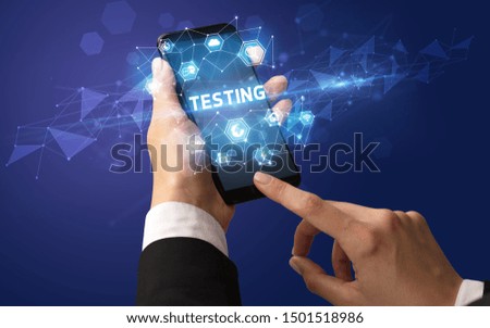 Female hand holding smartphone with TESTING inscription, modern technology concept