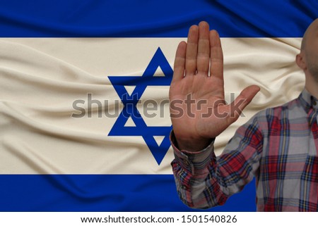 male hand with a gesture of protest, oaths against the backdrop of a silk national flag, the concept of denial and prohibition and prohibition, close-up, copy space
