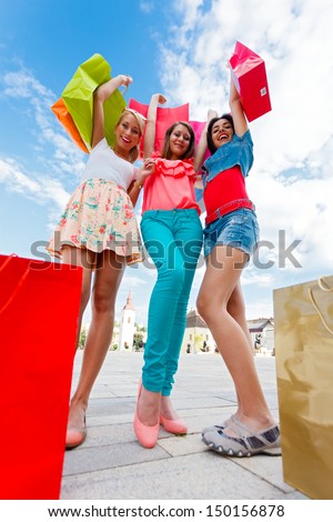 Excited young women after a big shopping with lifted shopping bags.