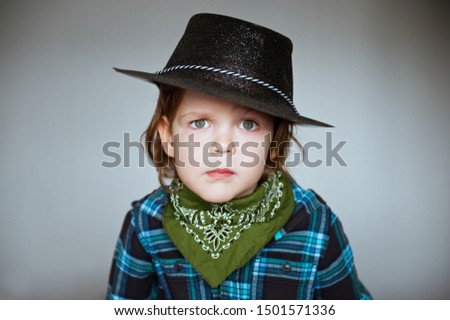 Portrait of a serious child in a cowboy costume. Bad mood.