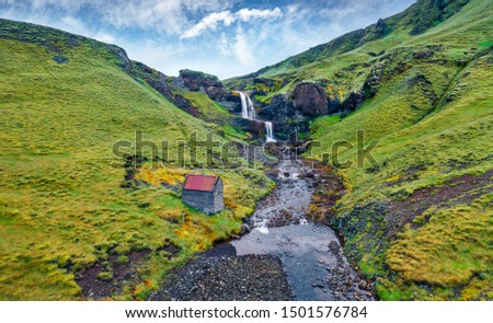 View from flying drone. Splendid morning view of nameless waterfall on Rauda river. Fresh green hills on the southern coast of Iceland at June. Beauty of nature concept background.