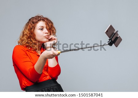 Redhead girl taking selfie on phone on monopod