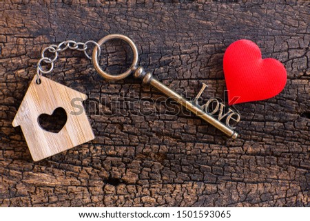 House key in heart shape with home keyring on old wood background decorated with mini heart, home sweet home concept, copy space
