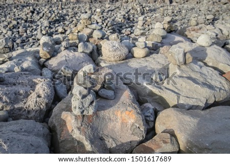 Stones put on top of each other, form pyramids standing on large boulders on the waterfront