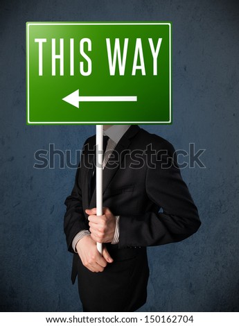 Businessman standing and holding a green direction sign in front of his head