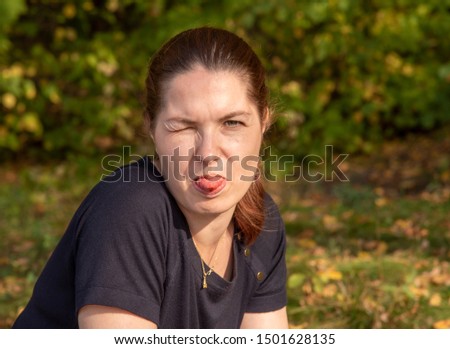 Portrait of a middle-aged woman who has closed one eye and shows her tongue.Funny picture.