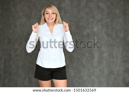 Portrait of a pretty blonde manager girl in a white blouse on a gray background. Right in front of the camera in various poses.