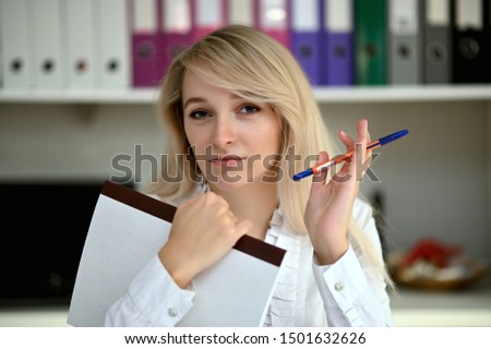 Portrait of a pretty manager blonde girl at work in a white blouse in the office at the table. Right in front of the camera in various poses.