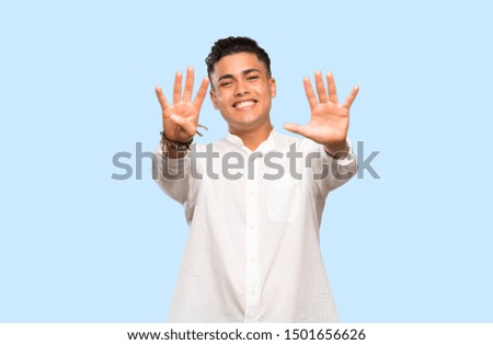 Young man counting nine with fingers on colorful background