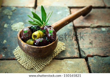 Variety of olives in an old wooden ladle with black, green and stuffed olives served as a savoury appetizer