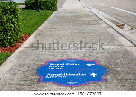 Sidewalk marker showing the way for destinations in downtown Boca Raton, FL