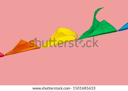 Colorful triangles flags ornament for carnival and holiday hang on a rope and flutter in the wind outdoors, isolated on a pink background by clipping