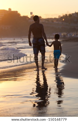 Father and son on the beach at sunset