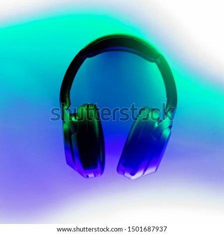 Wireless headphones lighted with neon light of green and purple colors, top view