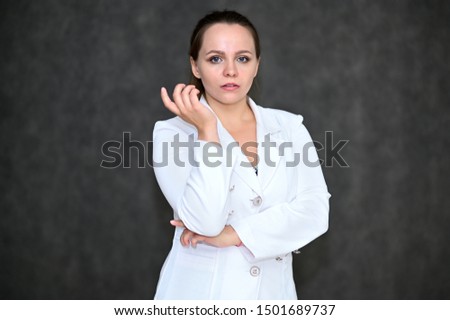 Business Portrait of a pretty female manager on a gray background in a white business suit. Standing right in front of the camera in various poses.